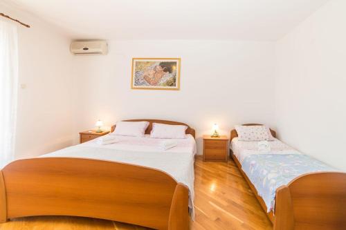 Habitación con 2 camas, paredes blancas y suelo de madera. en Rooms Glavan 63, en Rovinj