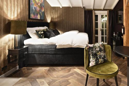 a bedroom with a bed and a chair and a table at Small Luxury Boutique Hotel Wilma J in Vinkeveen