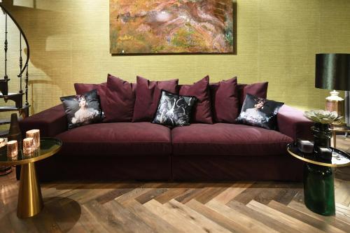 a living room with a purple couch with pillows at Small Luxury Boutique Hotel Wilma J in Vinkeveen