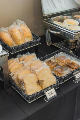 a table with trays of breads and pastries at Plaza Inn Trevo Sorocaba in Sorocaba