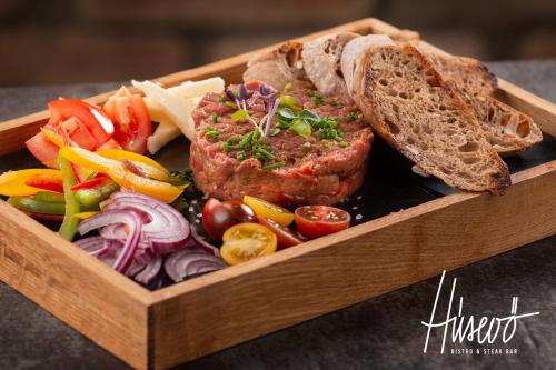 a wooden tray of food with meat and bread and vegetables at Hotel Garzon Plaza in Győr