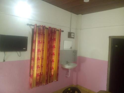 a bathroom with a sink and a tv on a wall at green valley home stay vagamon in Vagamon