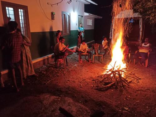 a group of people sitting around a fire at green valley home stay vagamon in Vagamon