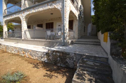a house with a stone wall and a balcony at Murter Inn in Murter
