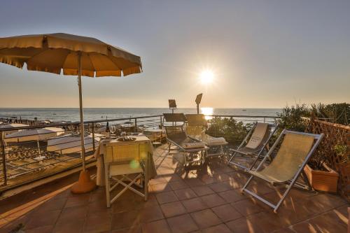a patio with chairs and an umbrella and the ocean at La Lanterna in San Vincenzo
