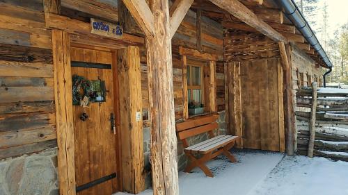 a wooden cabin with a bench in front of it at Chata Baba Yaga in Ždiar