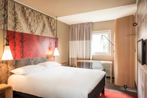 um quarto de hotel com uma cama branca e uma parede vermelha em Ibis Marrakech Centre Gare em Marraquexe