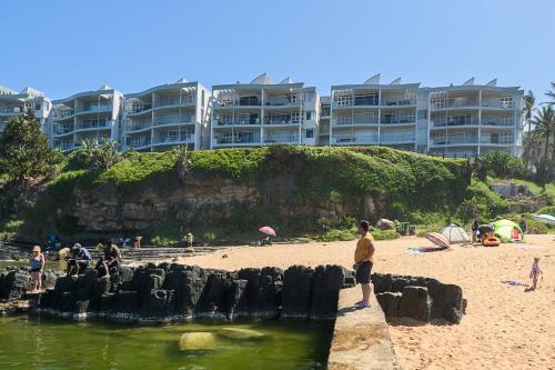 a group of people standing on a beach near the water at Chakas Cove in Ballito