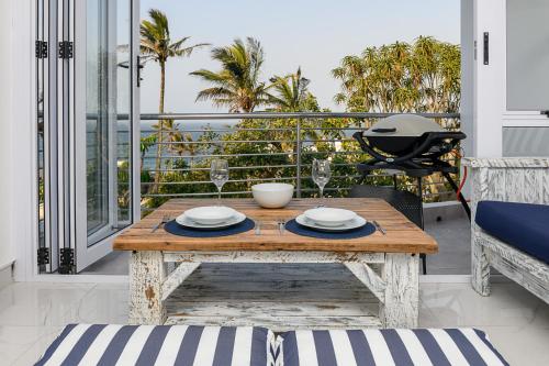 a dining table on a balcony with a view of palm trees at Chakas Cove in Ballito