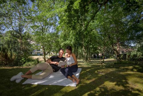 un groupe de personnes assises sur une couverture dans l'herbe dans l'établissement Hôtel du Parc, à Hardelot-Plage