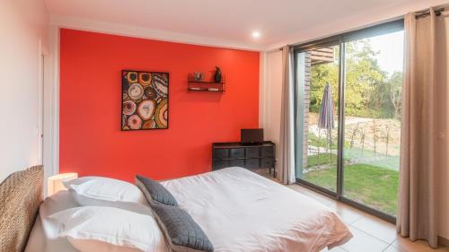 a bedroom with an orange wall with a bed and a window at Plein Soleil avec Jacuzzi Privatif et parking priv&eacute; in Sarlat-la-Can&eacute;da