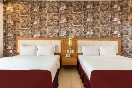 two beds in a hotel room with a wallpaper at Lam Kinh Hotel in Ho Chi Minh City