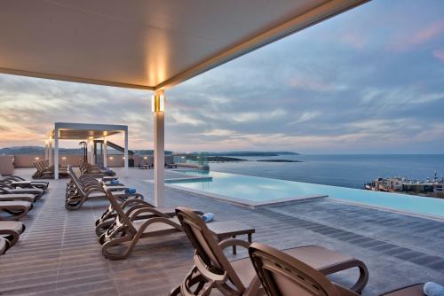 a deck with chairs and a swimming pool on a building at Mayflower Hotel Malta in St Paul's Bay
