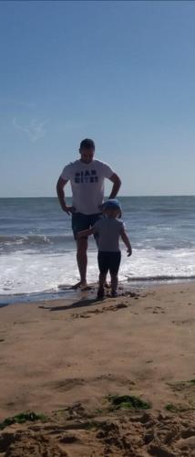 a man and a child standing on the beach at Chez Kiki et Ioannis in Naxos Chora