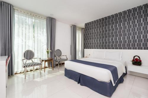 a bedroom with a bed and chairs and a large window at Lam Kinh Hotel in Ho Chi Minh City