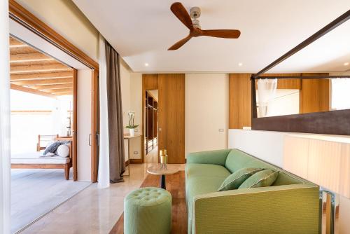 a living room with a green couch and a ceiling fan at Il San Corrado di Noto in Noto