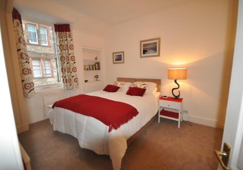 a bedroom with a large bed with a red blanket at Rockpool Apartment in North Berwick