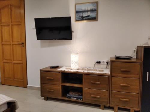 a living room with a tv and a wooden dresser at Gólya Vendégház in Tiszaug