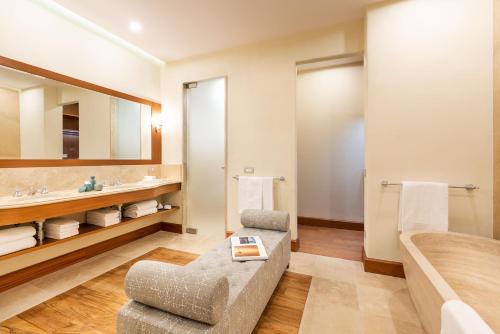 a bathroom with a couch and a tub and a sink at Il San Corrado di Noto in Noto