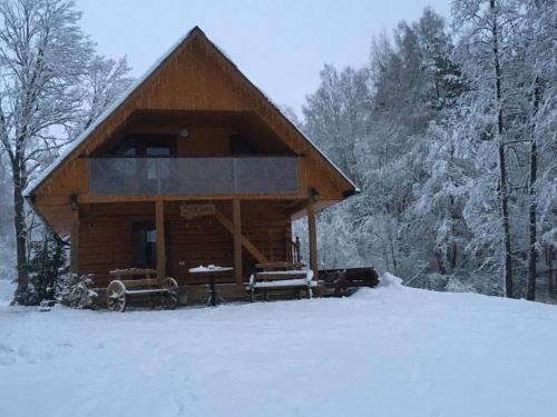 a log cabin in the snow with two benches at "Čiekuri" in Aglona