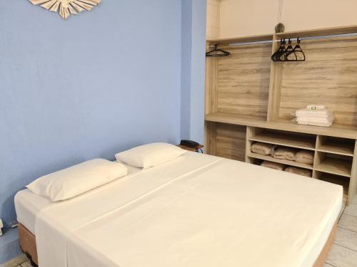 a white bed in a room with a shelf with towels at Pousada Nossa Senhora Aparecida in Águas de São Pedro