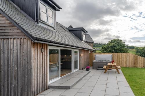 a house with a patio with a couch and a table at The Annexe, Luxury Property with Hot Tub at Pitilie Pods in Aberfeldy