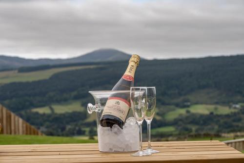 a bottle of champagne and two glasses on a table at The Annexe, Luxury Property with Hot Tub at Pitilie Pods in Aberfeldy
