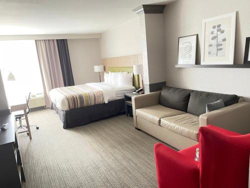 a hotel room with a bed and a couch at Country Inn & Suites by Radisson, Greenville, NC in Winterville