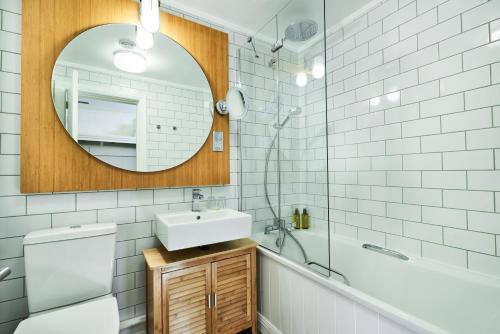 a bathroom with a sink, mirror, and bathtub at Isle Of Mull Hotel and Spa in Craignure
