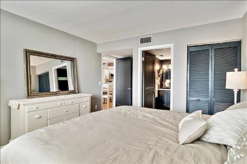 Un dormitorio con una cama con espejo y una cómoda. en Unit 3206 - Ocean & Racquet Resort, en St. Augustine Beach