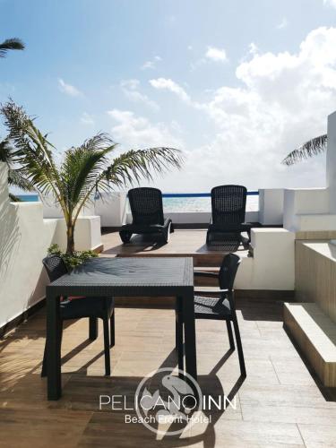 a table and chairs on a balcony with the ocean at Pelicano Inn Playa del Carmen - Beachfront Hotel in Playa del Carmen
