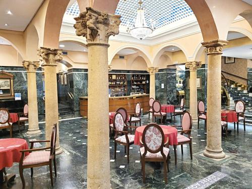 un restaurante con mesas rojas y sillas en un edificio en Hotel Imperial en Valladolid