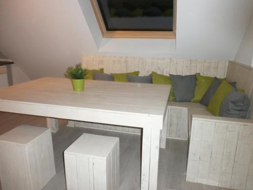 a white table and a couch with green pillows at 't Vossenerf in De Haan
