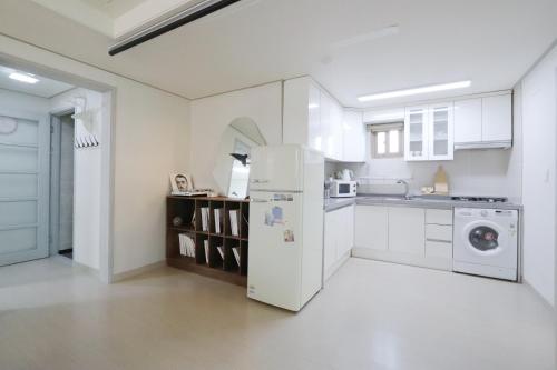 a white kitchen with a refrigerator and a sink at Lovely House Hongdae in Seoul