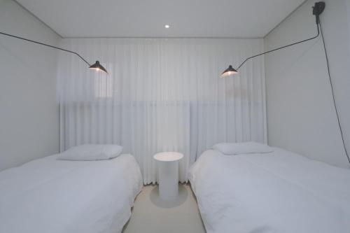 2 letti in una camera con pareti e luci bianche di Lovely House Hongdae a Seul
