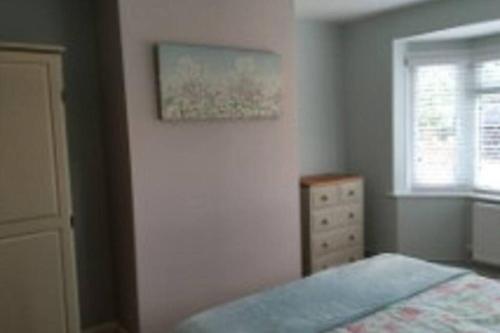 a bedroom with a bed and a painting on the wall at BROOK COTTAGE in Whitstable