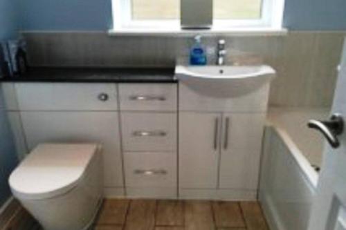 a bathroom with a toilet and a sink and a tub at BROOK COTTAGE in Whitstable