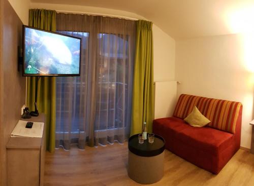 a living room with a couch and a flat screen tv at Hotel-Restaurant Bellevue in Ruhpolding