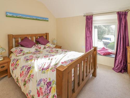 a bedroom with a bed and a window with purple curtains at 1 Rhys Terrace in Pennal