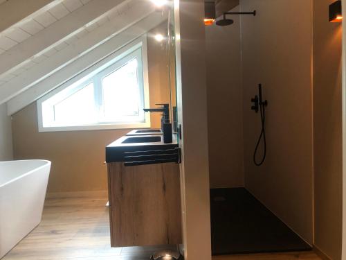 a bathroom with a sink and a tub and a window at Le champ Madame in Stavelot