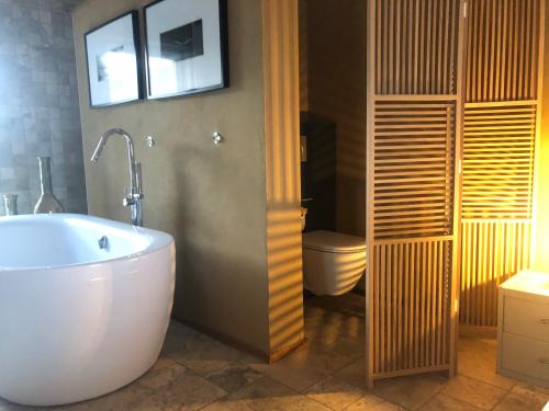 a bathroom with a white tub and a toilet at Le champ Madame in Stavelot