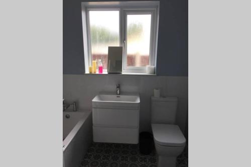 a bathroom with a toilet and a sink and a window at Oyster Beach Cottage in Whitstable