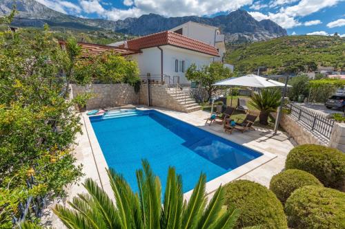 una piscina frente a una casa con montañas en Villa OLD OLIVE, 3lovelyvillas, en Podgora