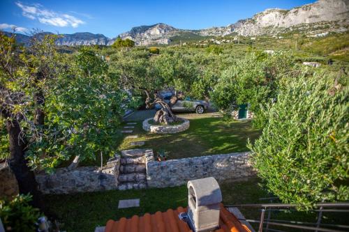 a view of a garden with a statue and trees at Villa OLD OLIVE, 3lovelyvillas in Podgora