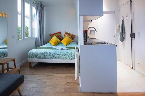 Dormitorio pequeño con cama con almohadas amarillas en Apartments au Dream of horse, Dream of golf, Proche Hippodrome, Saint Cloud, en Saint-Cloud