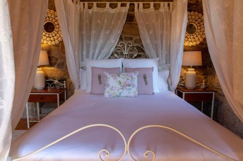 a bedroom with a white bed with white curtains at Casa Rural as Bentinas in Milladoiro