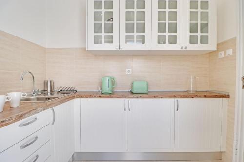 uma cozinha branca com armários brancos e um lavatório em The Fig and Almond Houses em Vila Real de Santo António