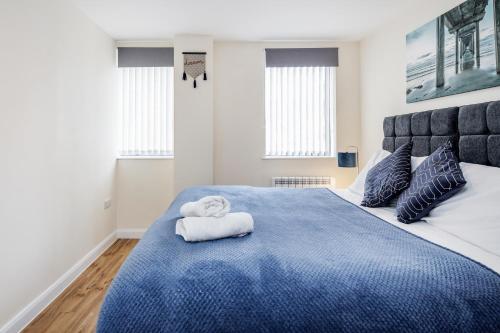 sypialnia z niebieskim łóżkiem i ręcznikami w obiekcie Queens Serviced Apartments - F1 w mieście Watford