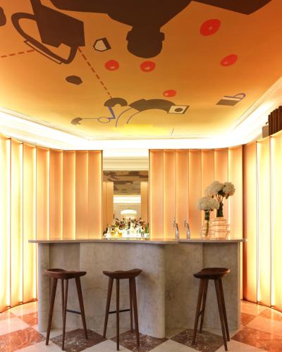 a bar with three stools in a room with a ceiling at Hôtel Vernet Champs Elysées Paris in Paris