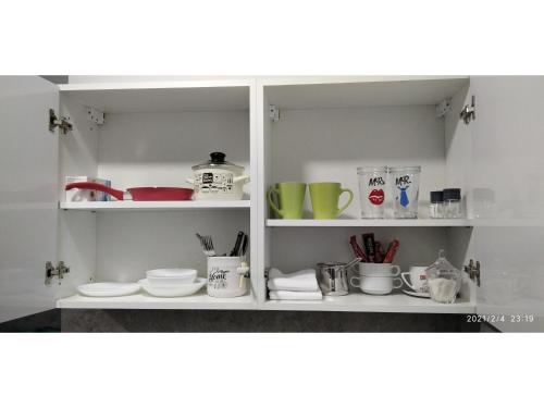a kitchen shelf with dishes and cups and plates at Slatka Tajna in Banja Luka